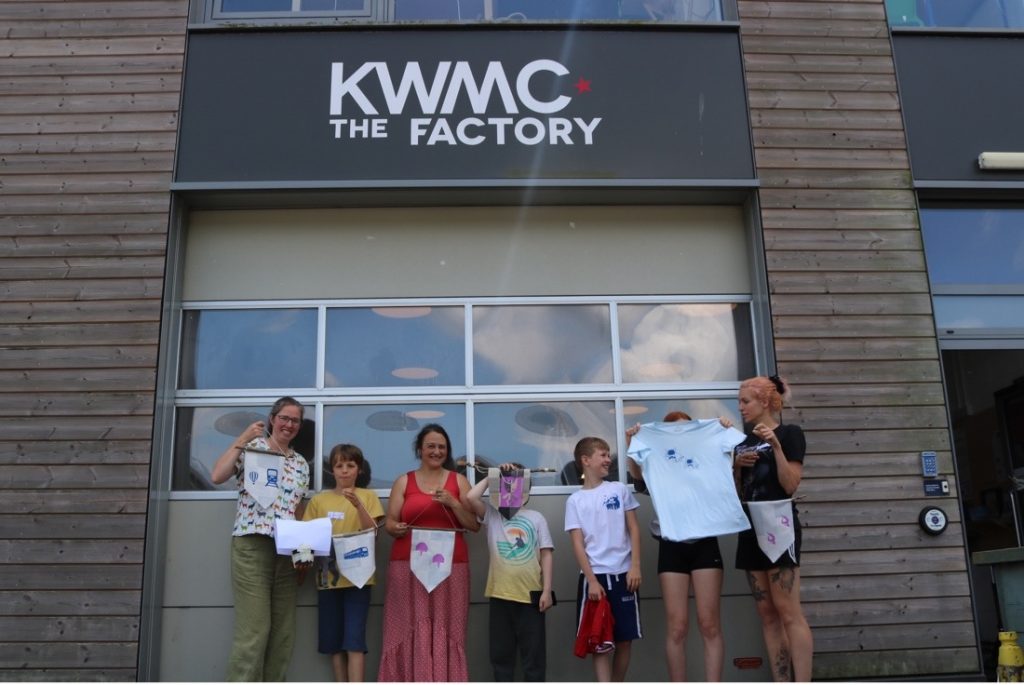 A group of people outside of KWMC The Factory showing what they have created.